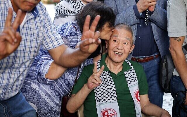 Une femme embrasse Kozo Okamoto à la tête - c'est le seul survivant du commando de trois hommes qui avait tué 26 personnes à l'aéroport de Lod dans un attentat terroriste commis par les membres de l'Armée rouge japonaise, lors d'une cérémonie organisé par des militants palestiniens pour marquer le 50e anniversaire de l'attaque à Beyrouth, au Liban, le 30 mai 2022. (Crédit :  JOSEPH EID / AFP)