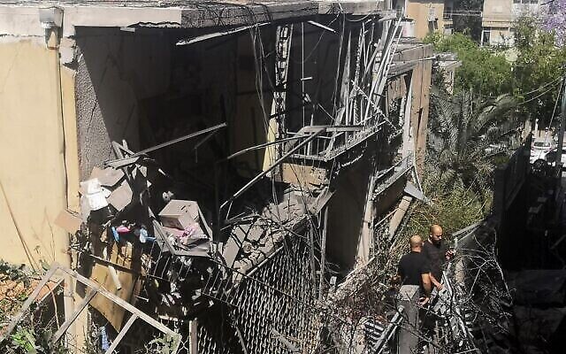 Dans la banlieue de Givatayim, à Tel Aviv, des Israéliens inspectent une maison endommagée le 12 mai 2021, touchée par une roquette tirée par des terroristes palestiniens depuis la bande de Gaza. (Crédit : Alexandra Vardi/AFP)