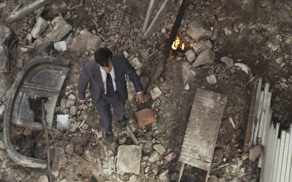Gustavo Bassani dans le rôle de Yosi dans la nouvelle série Amazon Prime Video, "Yosi, the Regretful Spy", marche dans les décombres après l'attaque de l’Argentine Israelite Mutual Association. (Crédit : Autorisation de Daniel Burman/Amazon)