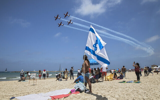 Dossier : Des personnes sur une plage de Tel Aviv regardent un spectacle aérien militaire lors de Yom HaAstmaout, le 2 mai 2017. (Crédit: AP Photo/Dan Balilty)