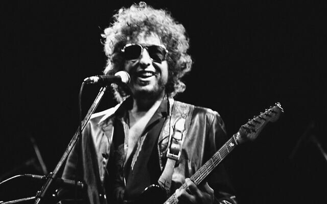 Le chanteur américain Bob Dylan souriant lors de son spectacle au stade olympique de Colombes, en France, le 24 juin 1981. (Crédit: AP Photo/Herve Merliac, File)