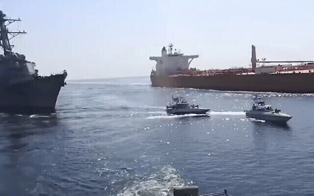 Les bateaux de patrouille des Gardiens de la révolution islamique devant un navire de guerre américain, à gauche, dans le Golfe d'Oman, pendant la saisie d'un pétrolier vietnamien par l'Iran, à droite, dans le Golfe d'Oman, le 3 novembre 2021. (Capture d'écran : Vidéo des Gardiens de la révolution via AP)