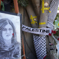 Du ruban jaune marque les impacts de balles sur un arbre et un portrait et des fleurs forment un mémorial de fortune sur le site où la journaliste palestino-américaine d'Al-Jazeera Shireen Abu Akleh a été tuée par balle dans la ville de Jénine, en Cisjordanie, le jeudi 19 mai 2022. (Crédit: AP/Majdi Mohammed)
