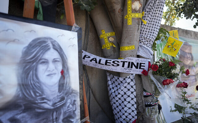 Du ruban jaune marque les impacts de balles sur un arbre et un portrait et des fleurs forment un mémorial de fortune sur le site où la journaliste palestino-américaine d'Al-Jazeera Shireen Abu Akleh a été tuée par balle dans la ville de Jénine, en Cisjordanie, le jeudi 19 mai 2022. (Crédit: AP/Majdi Mohammed)
