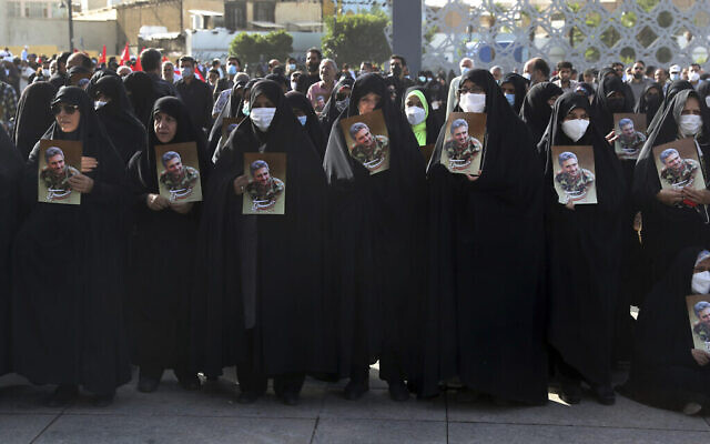 Des femmes en deuil  tiennent des affiches à l'effigie du colonel des Gardiens de la révolution iranienne, Hassan Sayyad Khodaei, lors de la cérémonie funèbre à Téhéran, en Iran, le mardi 24 mai 2022. (Crédit : AP/Vahid Salemi)