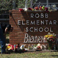 Un policier allume une bougie aux abords de la Robb Elementary School à Uvalde, au Texas, le 25 mai 2022. (Crédit : AP/Jae C. Hong)
