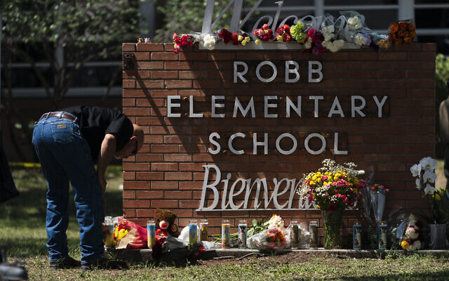Un policier allume une bougie aux abords de la Robb Elementary School à Uvalde, au Texas, le 25 mai 2022. (Crédit : AP/Jae C. Hong)