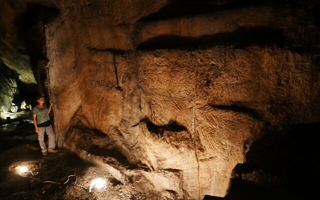 Ayala Amir dans la grotte de Teomim, avec des traces d'activités d'extraction visibles sur le murs et sur le sol. (Crédit : Prof. Boaz Zissu, Bar-Ilan University)