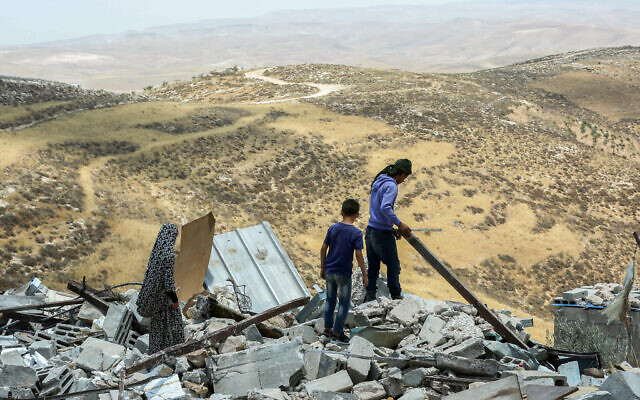 Des Palestiniens regardent des maisons qui ont été démolies par les autorités israéliennes dans le village cisjordanien de Khalat Aldabe, au sud de Yatta, le 17 juin 2019. (Crédit: Wissam Hashlamon/Flash90)