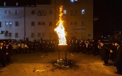 Des personnes dansent près d'un grand feu de joie, lors des célébrations de la fête juive de Lag BaOmer dans le quartier ultra-orthodoxe de Mea Shearim à Jérusalem, le 19 mai 2022. (Crédit: Olivier Fitoussi/Flash90)