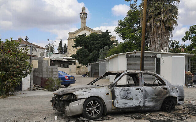 Une voiture incendiée lors des affrontements entre résidents juifs et arabes de Lod, dans la ville israélienne de Lod, dans le centre du pays, le 23 mai 2021. (Crédit : Flash90)