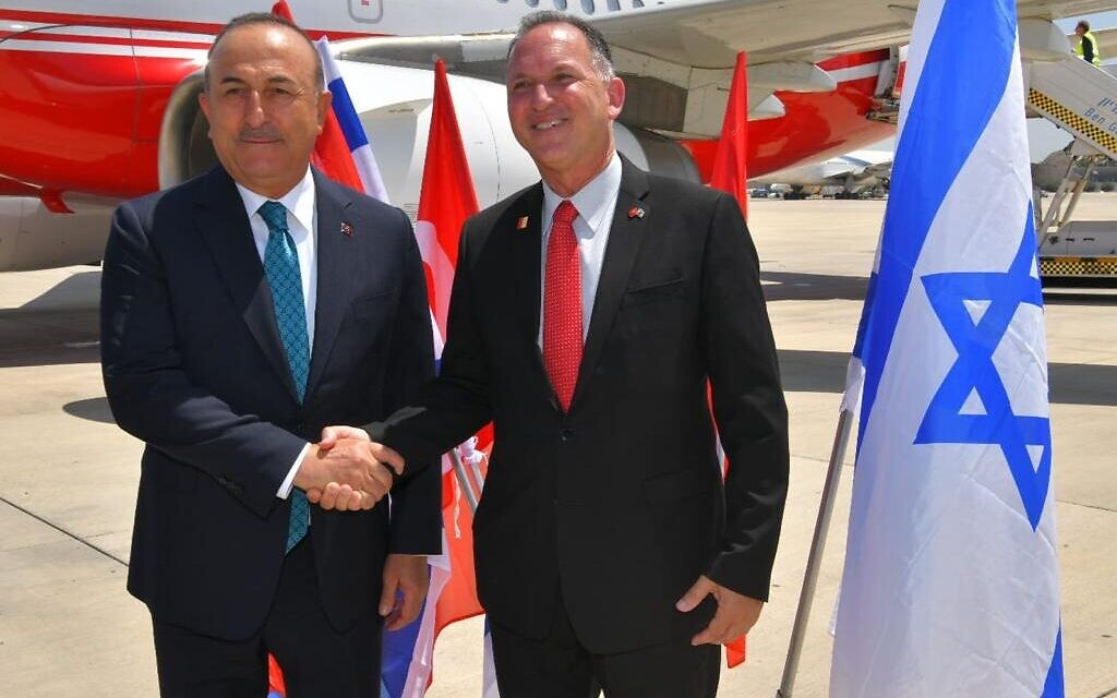 Le ministre turc des Affaires étrangères  Mevlut Cavusolgu est accueilli en Israël par Gil Haskel, chef du protocole du ministère des Affaires étrangères, le 24 mai 2022. (Crédit : Shlomi Amsalem/GPO)
