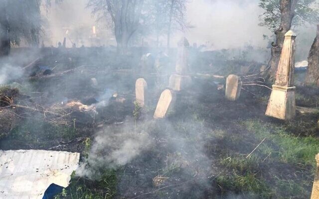 De la fumée s'élève au-dessus des stèles d'un cimetière juif qui aurait été bombardé à Hulkhiv, en Ukraine, le 8 mai 2022. (Crédit : Dmitry Zhivitsky / Facebook )