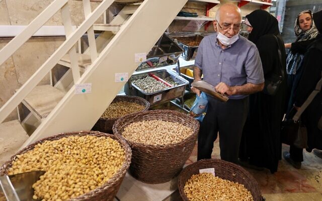 Un employé du plus ancien grossiste en pistaches d'Iran prépare une commande pour les clients du magasin dans le célèbre Graz Bazar de Téhéran, le 19 juin 2022. (Crédit : ATTA KENARE / AFP)