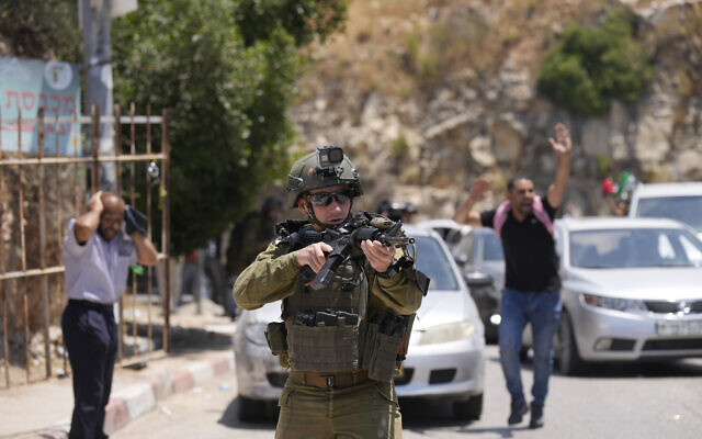 Un soldat israélien braque son arme pendant les obsèques d'Auda Sadaqa, 17 ans, à un checkpoint du village d'Al-Madiya en Cisjordanie, près de Ramallah, le 3 juin 2022. ,