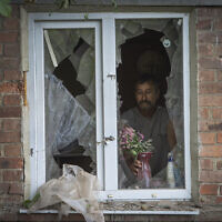 Un habitant place un vase avec des fleurs sur une fenêtre brisée de sa maison endommagée par les bombardements russes à Bakhmut, dans la région de Donetsk, en Ukraine, dimanche 26 juin 2022 (AP Photo/Efrem Lukatsky).