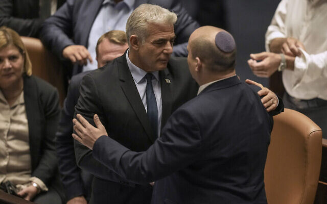 Le Premier ministre sortant Naftali Bennett, à droite, et son successeur intérimaire Yair Lapid prennent la parole après l’adoption d’un projet de loi visant à dissoudre la Knesset, le 30 juin 2022. (Crédit : AP Photo/Ariel Schalit)