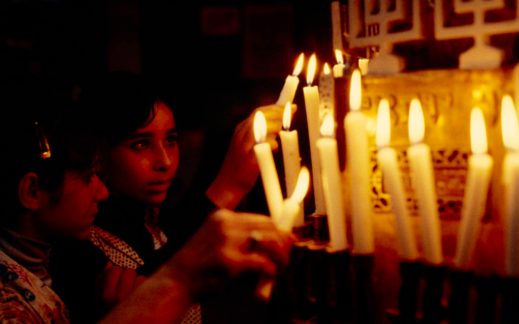 Deux jeunes filles forment des vœux en posant une bougie, lors du pèlerinage annuel à la Ghriba. (Crédit : Jacques Pérez / Musée d’art et d’histoire du judaïsme, Paris)