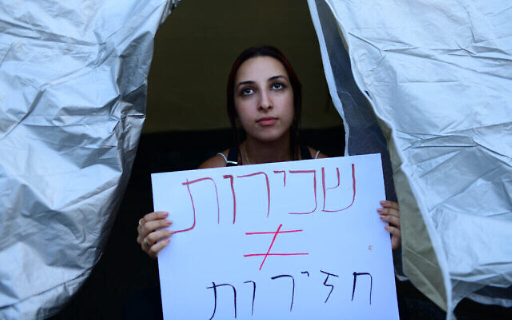 Des Israéliens installent des tentes sur le boulevard Rothschild à Tel Aviv, pour protester contre la flambée des prix du logement en Israël et les inégalités sociales, le 19 juin 2022. La pancarte proteste contre la flambée des prix des loyers, et se traduit approximativement par "Les propriétaires n'ont pas besoin d'être des porcs" (Crédit: Tomer Neuberg/ Flash90)
