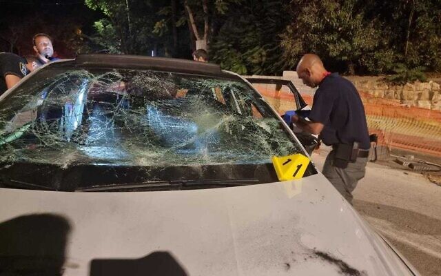 Des policiers inspectant une voiture endommagée par des pierres à Jérusalem-Est, le 8 juin 2022. (Crédit: Police israélienne)