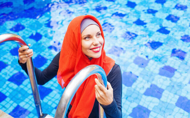 Une femme en burkini et hijab dans une piscine. (Crédit : LiudmylaSupynska/iStock)