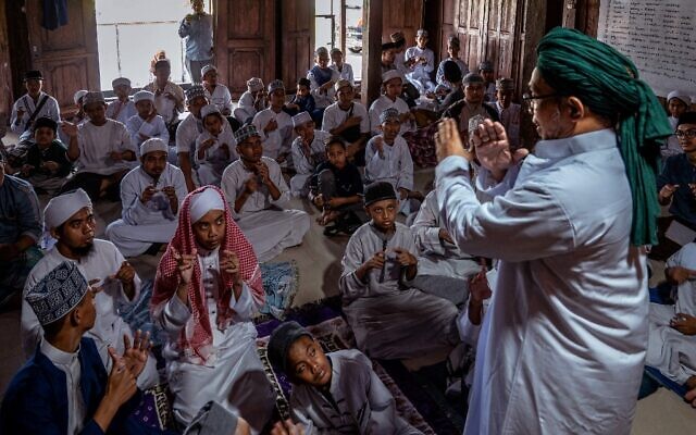 Le fondateur d'un pensionnat islamique pour enfants sourds, Abu Kahfi (R), en train d'enseigner à des élèves dans  à Sleman, en Indonésie, le 22 juin 2022. (Crédit : JUNI KRISWANTO / AFP)