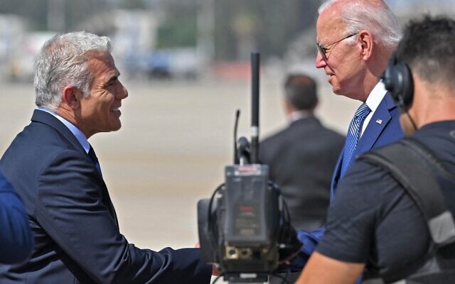 Le Premier ministre Yair Lapid salue le président américain Joe Biden à son arrivée à l'aéroport Ben Gurion de Lod, près de Tel Aviv, le 13 juillet 2022. (Crédit : MANDEL NGAN / AFP)