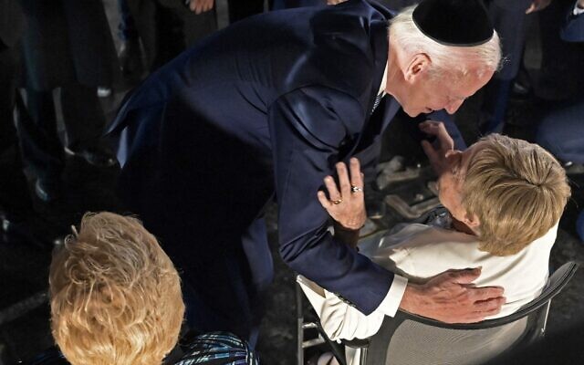 Le président américain Joe Biden étreint Giselle Cycowicz, survivante de la Shoah, sous le regard de Rena Quint pendant une cérémonie dans la salle du souvenir du musée de Yad Vashem à Jérusalem, le 13 juillet 2022. (Crédit :  DEBBIE HILL / POOL / AFP)