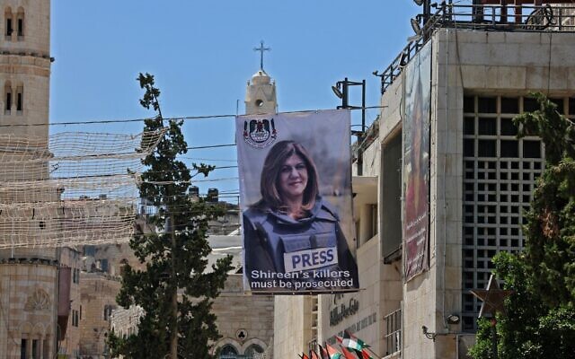 Une bannière montrant la journaliste d'Al Jazeera tuée par balle Shireen Abu Akleh accrochée à un bâtiment surplombant l'église de la Nativité à Bethléem, en Cisjordanie, le 14 juillet 2022. (Crédit :  Ahmad Gharabli/AFP)