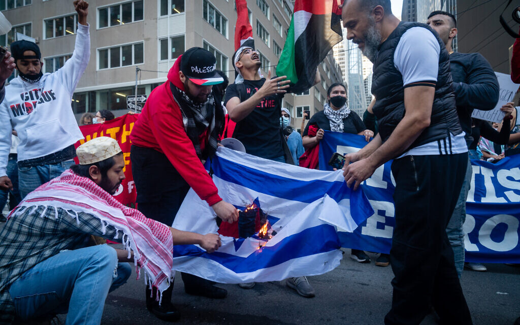 Des militants anti-israéliens et pro-palestiniens brûlant un drapeau israélien, à New York, le 15 mai 2021. (Crédit: Luke Tress/Times of Israel)