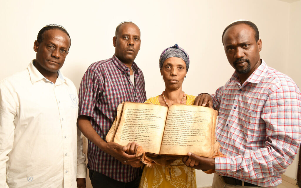 Ayanawo Ferada Senebato, à droite, et sa famille à Ashkelon, en Israël, tenant un ancien livre d'Orit qu'ils ont récupéré près de Gondar, en Éthiopie, en février 2022. (Crédit : Yossi Zeliger via JTA)