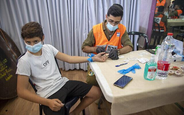 Illustration : Un soldat israélien effectue un test d’anticorps contre la COVID-19 sur un jeune garçon à Hadera, en Israël, le lundi 23 août 2021. (Crédit : AP Photo/Ariel Schalit)