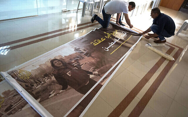 Des Palestiniens préparent des affiches avec des photos de la journaliste d’Al Jazeera, Shireen Abu Akleh et une légende en arabe disant "Shireen, le pouls de la Palestine", au siège de la chaîne Al Jazeera, dans la ville de Ramallah en Cisjordanie, le mercredi 11 mai 2022. (Crédit : AP/Nasser)