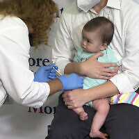 Ellen Fraint tient sa fille, Jojo, âgée de sept mois, alors qu'elle reçoit la première dose du vaccin Moderna COVID-19 au Montefiore Medical Group à New York, le 21 juin 2022. (Crédit: AP Photo/Ted Shaffrey)