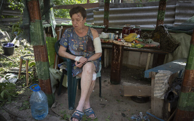 Une femme blessée quand sa maison a été détruite par les obus russe est assise, choquée, dans son jardin à Bakhmut, dans la région de Donetsk, en Ukraine, le 26 juin 2022. (Crédit : AP Photo/Efrem Lukatsky)
