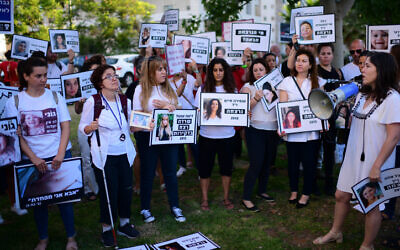 Des manifestantes brandissent des pancartes avec des photos de femmes tuées, lors d'une manifestation contre les violences faites aux femmes et les féminicides, à Tel Aviv, le 25 juin 2022 (Crédit : Tomer Neuberg/FLASH90)