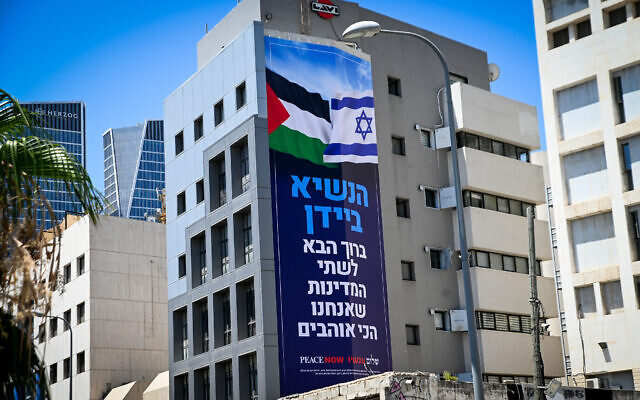 Une bannière où l'on peut lire "Président Biden, bienvenue dans les deux États que nous aimons le plus", comprenant un drapeau israélien et un drapeau palestinien, dans le cadre d'une campagne menée par le mouvement de gauche La Paix Maintenant, à l'approche de la visite officielle du président américain Joe Biden, est exposée à Tel Aviv, le 11 juillet 2022. (Crédit : Avshalom Sassoni/Flash90)