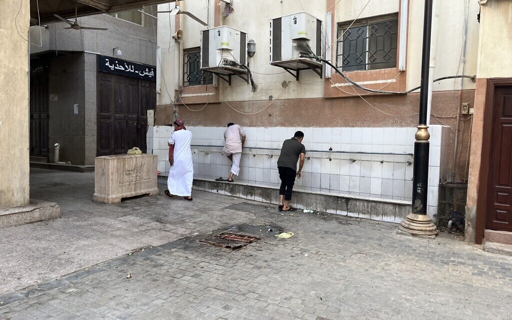 Des fidèles se lavent les pieds à l'entrée d'une mosquée du quartier Al Balad  de Jeddah, en Arabie saoudite, le 16 juillet 2022. (Crédit :  Jacob Magid/Times of Israel)