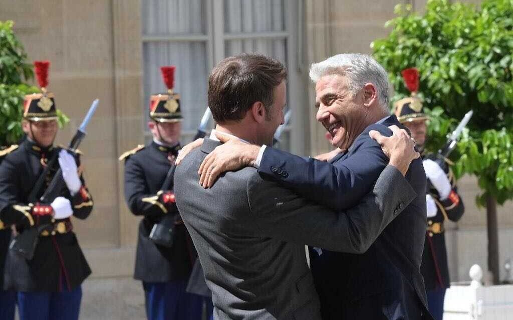 Le Premier ministre Yair Lapid, à droite, embrasse le président français Emmanuel Macron lors d'une conférence de presse à l'Elysée à Paris, France, le 5 juillet 2022. (Crédit: Amos Ben Gershom/GPO)