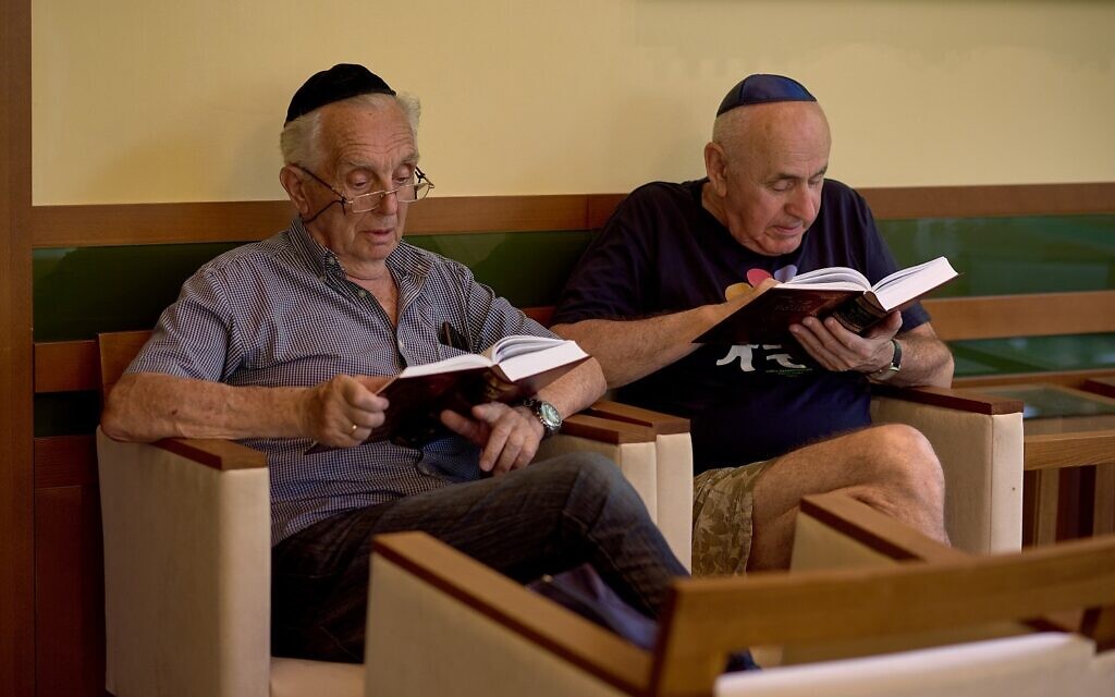 Deux hommes lisent dans un camp pour les réfugiés juifs ukrainiens à  Balatonőszöd, en Hongrie, au mois de juin 2022. (Autorisation : EMIH)