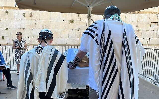 Seth Mann, à gauche, lisant un rouleau de la Torah lors de sa cérémonie de bar-mitzvah dans la section égalitaire du Mur occidental, le 30 juin 2022. (Crédit : Avec l’aimable autorisation de la famille Mann)
