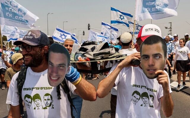 Des manifestants portant des dépouilles symboliques depuis Ashkelon arrivent au kibboutz Karmia, le 5 août 2022. (Crédit : Jack Guez/AFP)