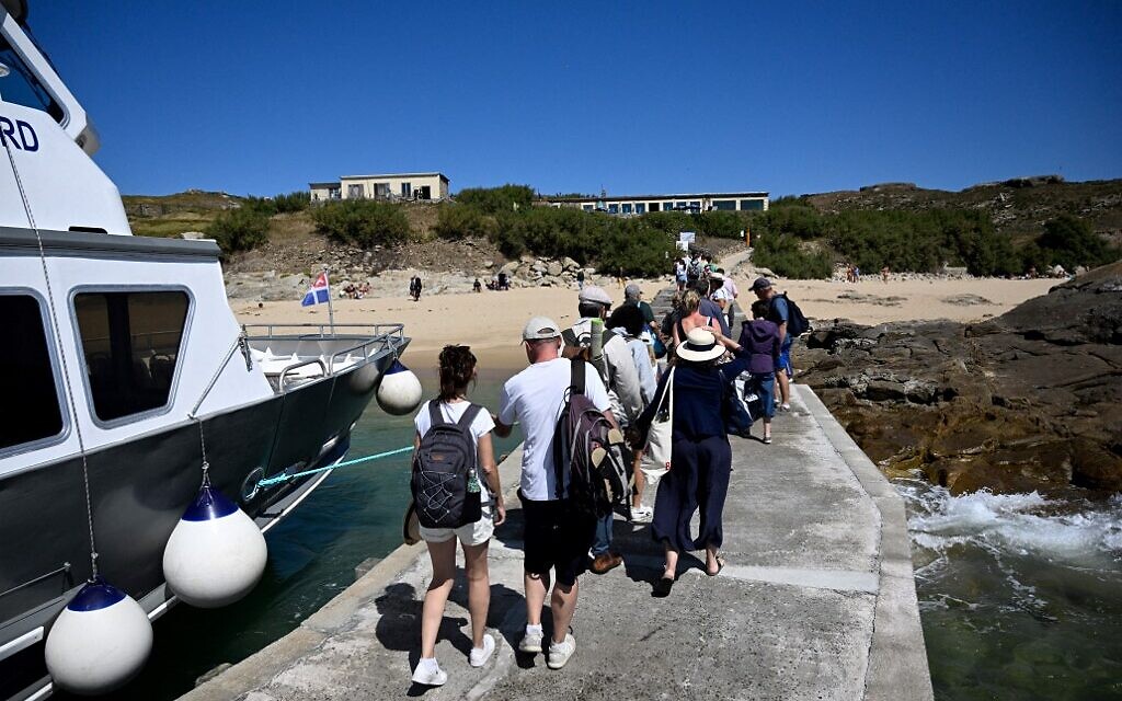 Des touristes débarquent sur la jetée de l'île Cezembre, au large de Saint-Malo, le 5 août 2022. (Crédit : Damien MEYER / AFP)
