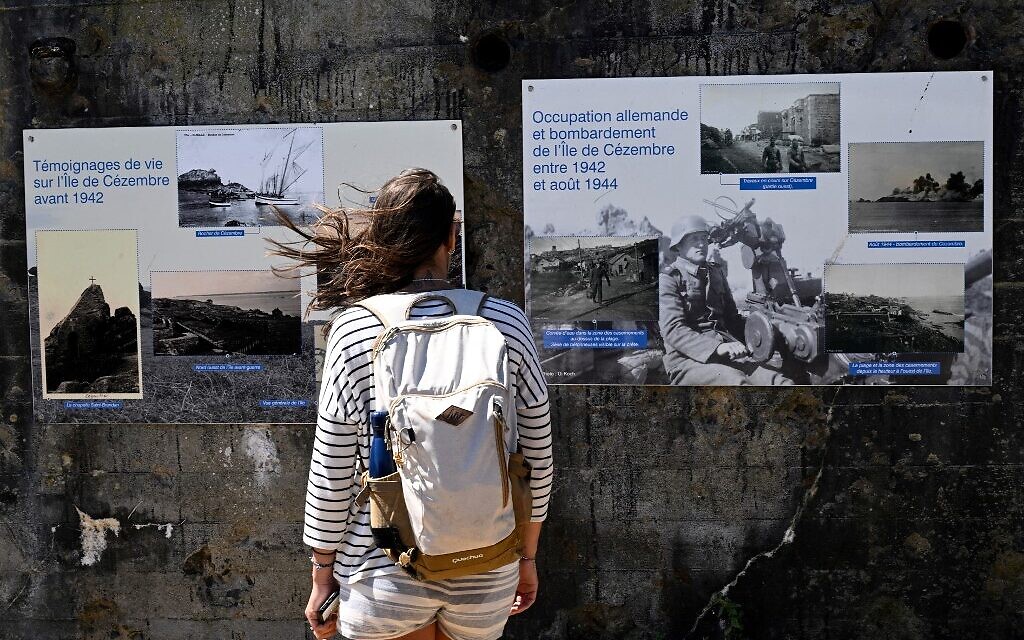 Un touriste lit des bannières informant les touristes de l'histoire de l'occupation allemande sur l'île de Cézembre, au large de Saint-Malo, le 5 août 2022. (Crédit : Damien MEYER / AFP)