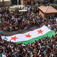 Des Syriens se rassemblent pour protester contre une proposition du ministre turc des Affaires étrangères de réconciliation entre le gouvernement syrien et l'opposition, dans la ville frontalière d'Azaz, dans le nord de la province d'Alep, tenue par les rebelles, le 12 août 2022. (Crédit : AFP)