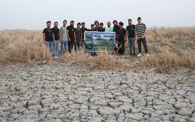 Des manifestants tenant une banderole portant le slogan en arabe "Sauvez les marais, la pénurie d'eau tue la vie dans les marais", pour demander des solutions à la pénurie d'eau et à la sécheresse, lors d'un rassemblement dans le marais d'Umm El Wadaa, au sud-est de la ville de Nasiriyah, dans la province de Dhi Qar, au sud de l'Irak, le 16 août 2022. (Crédit : Asaad NiaziI/AFP)