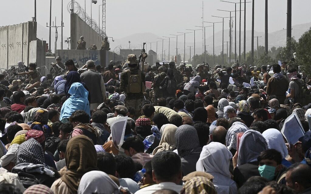 Des Afghans rassemblés au bord d'une route près de la partie militaire de l'aéroport de Kaboul dans l'espoir de fuir le pays après la prise de contrôle militaire de l'Afghanistan par les Talibans, le 20 août 2021. (Crédit : Wakil Kohsar/AFP)