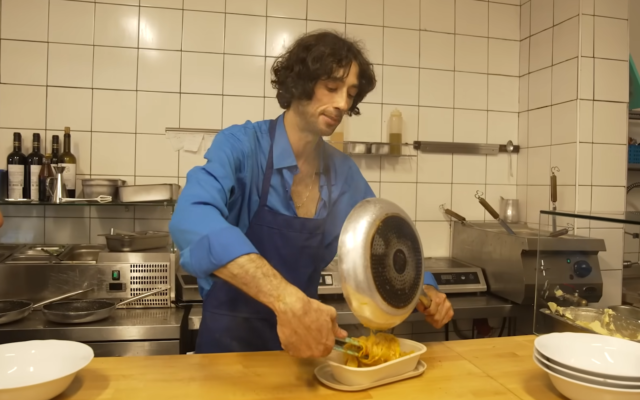 Tal Rachevski, le propriétaire de Tometomato open/closed prépare un plat de pâtes, dans un documentaire publié par la chaîne publique Kan le 9 août 2022. (Crédit : Capture d'écran)
