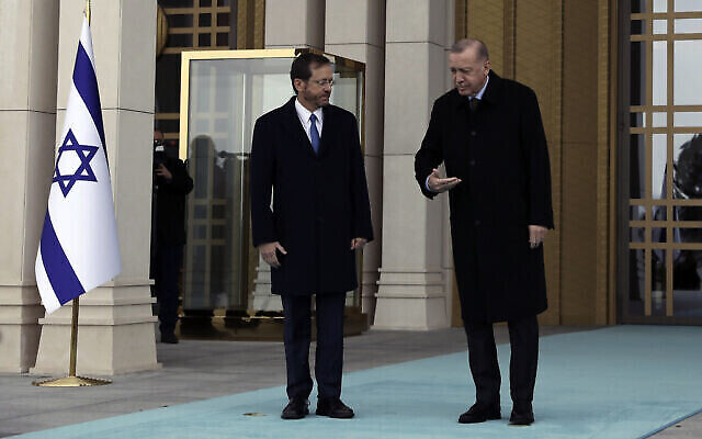 Le président turc Recep Tayyip Erdogan, à droite, indique le chemin au président Isaac Herzog lors d’une cérémonie de bienvenue, à Ankara, en Turquie, le 9 mars 2022. (Crédit : AP Photo/Burhan Ozbilici)