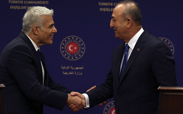Le ministre turc des Affaires étrangères r Mevlut Cavusoglu, à droite, et le ministre des Affaires étrangères israélien de l'époque, Yair Lapid, se serrent la main à Ankara, en Turquie, le 23 juin 2022. (Crédit :  AP Photo/Burhan Ozbilici)
